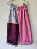 Colorful patterned pants hanging on a white hanger against a plain background
